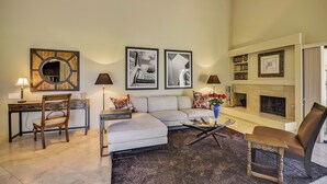 A living room with a sofa, chairs, a coffee table, a fireplace, and framed pictures on the wall. - Elegant Lakeside Villa (Rancho Mirage)