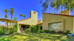 A modern house with a patio, palm trees, and a clear blue sky. - Elegant Lakeside Villa (Rancho Mirage)