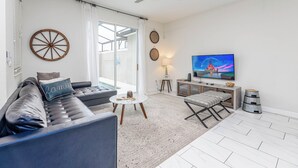 A modern living room with a leather sofa, a round wooden wall decoration, a television, and a ceiling fan. - Tvpm-4885rc/sl (Kissimmee)