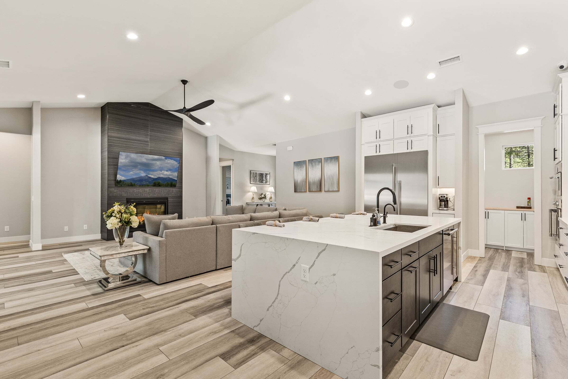 A modern kitchen with a central island, white cabinetry, and a built-in oven.
