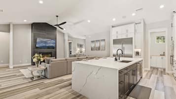 A modern kitchen with a central island, white cabinetry, and a built-in oven.