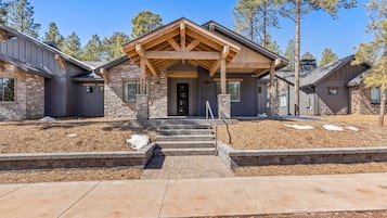 A two-story house with a stone facade, a wooden porch, and a stone staircase leading to the front door.