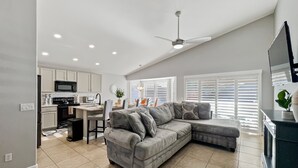 A modern living space with a kitchen, dining area, and a grey sectional sofa. - Kimberly Surprise (Surprise)