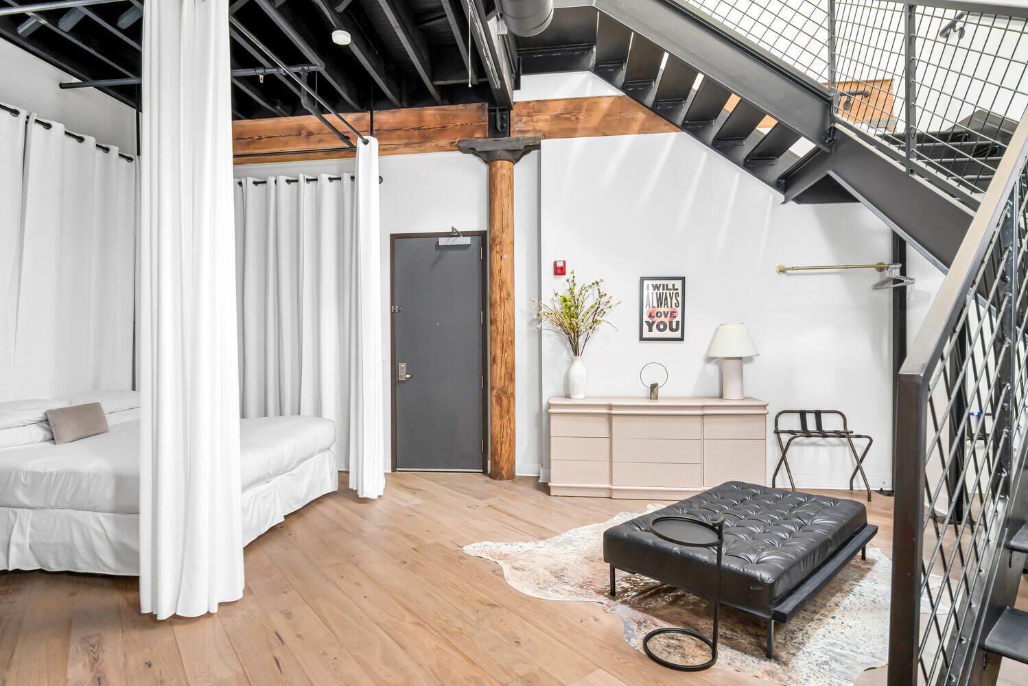 Camera da letto moderna tipo loft con un letto, un piccolo divano, una scrivania e una scala.