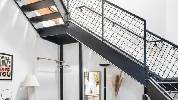 Un intérieur moderne avec un escalier noir, un canapé en cuir et une petite table.