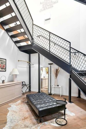 Ein modernes Interieur mit einer schwarzen Treppe, einem Ledersofa und einem kleinen Tisch.