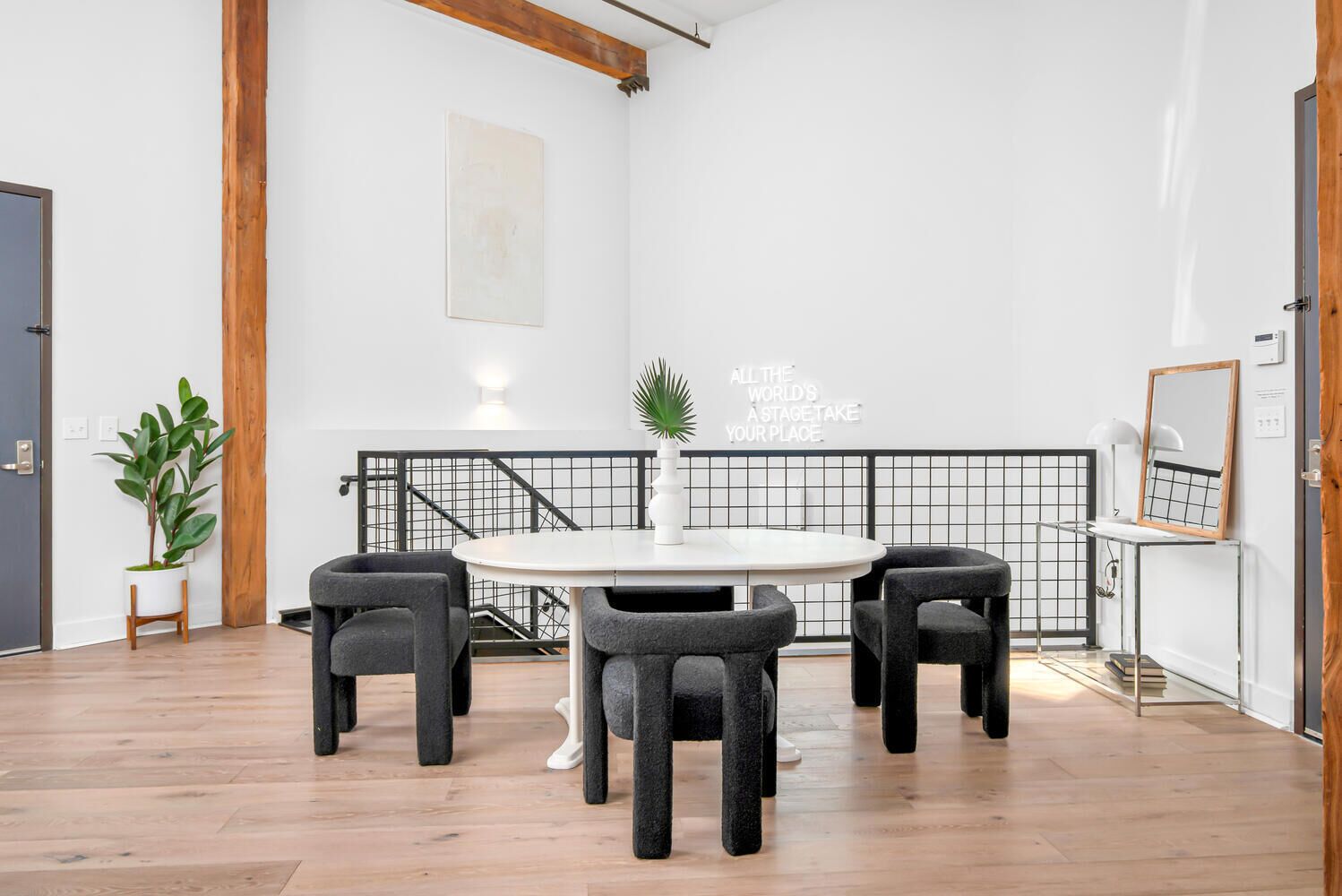 Une pièce moderne avec une table ronde, quatre chaises, une plante en pot et une citation inspirante sur le mur.