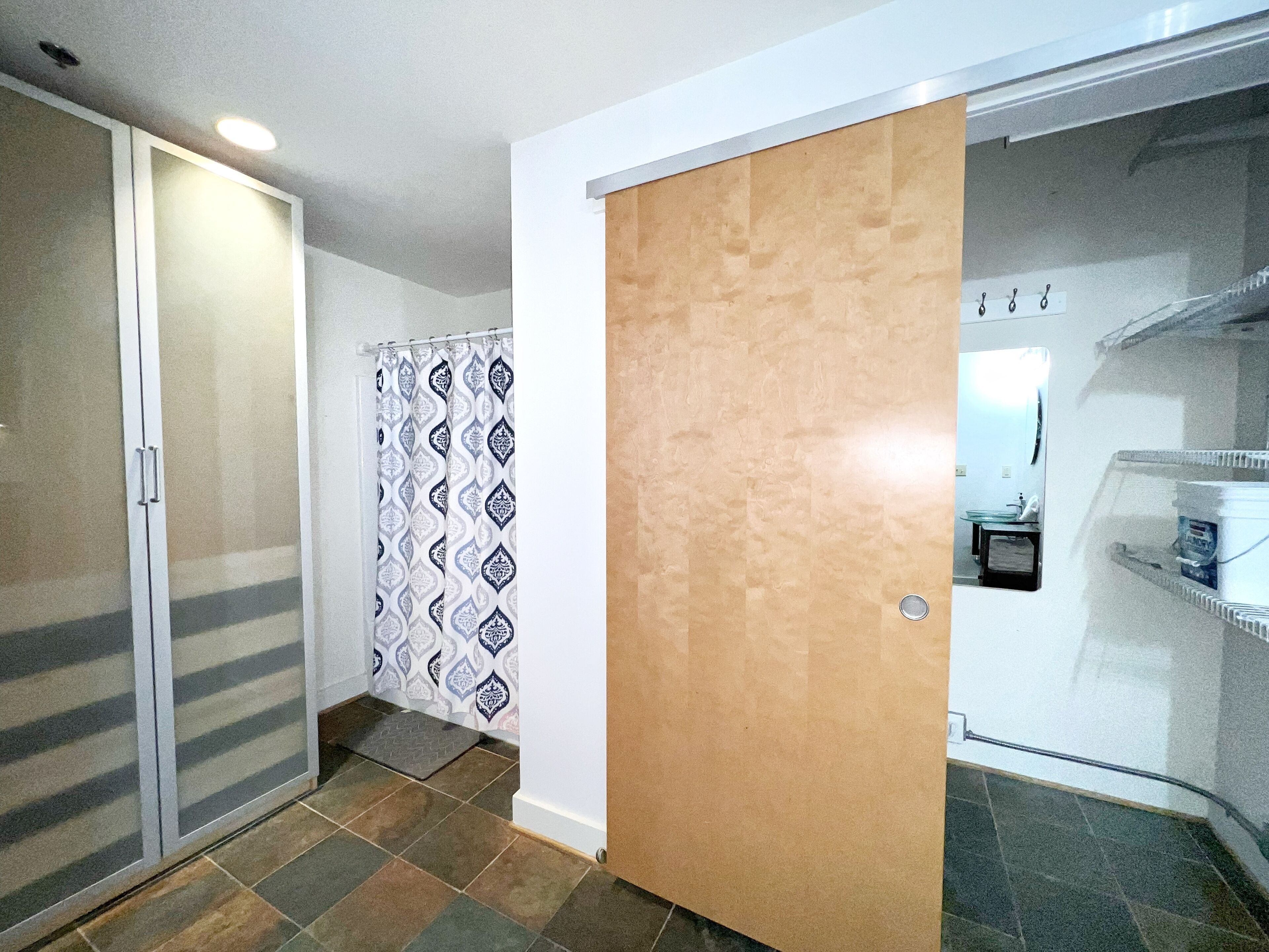 A room with a sliding door, a patterned shower curtain, and a tiled floor.