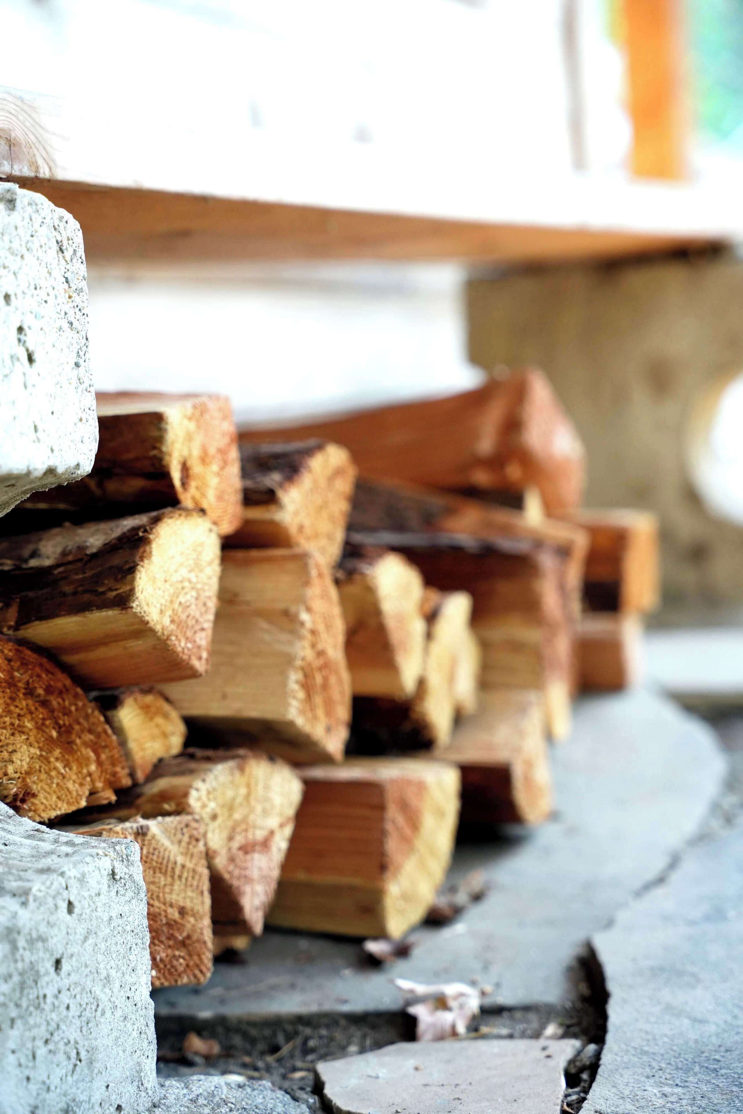 A stack of firewood against a concrete surface.