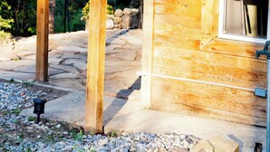 A wooden cabin with a metal roof, surrounded by a stone pathway and gravel, set in a forested area. - Cozy Cabin Retreat in Midway (Midway)