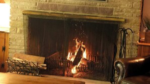 A living room with a stone fireplace, a flat-screen TV mounted above it, and a leather sofa. - Cozy Cabin Retreat in Midway (Midway)