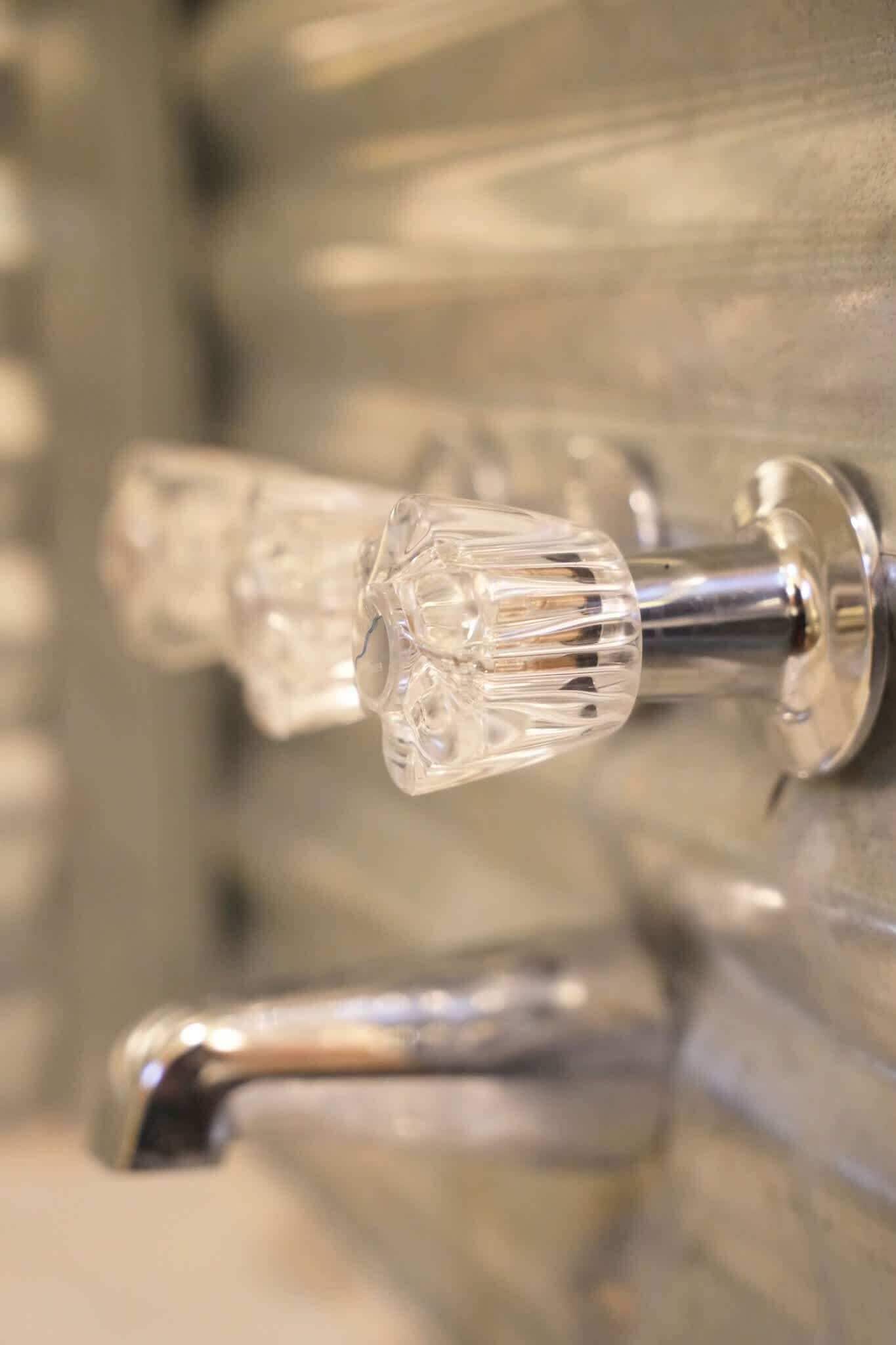 A close-up of a bathroom faucet with a clear, faceted design.