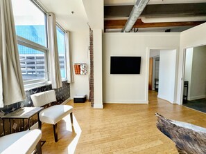 Ein modernes Wohnzimmer mit großem Fenster, einem an der Wand montierten Flachbildfernseher und Holzboden.