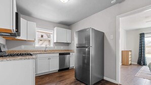 A modern kitchen with white cabinets, a stainless steel refrigerator, and a dishwasher. - Stylish 1-bedroom Retreat in Fort Worth (Fort Worth)