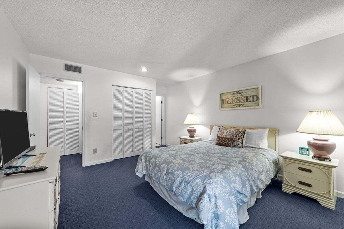 Ein Schlafzimmer mit einem Bett, zwei Nachttischen, einem Fernseher und einem Kleiderschrank.
