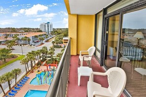 Ein Balkon mit Blick auf einen Swimmingpool und einen Parkplatz.