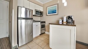 A kitchen with white cabinets, stainless steel appliances, and a tiled floor. - Caravelle 706 (Myrtle Beach)