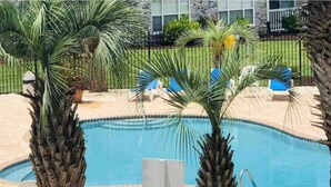 A swimming pool with palm trees and lounge chairs. - Captains Quarters Bright 2BR Pet-friendly Beach Condo w/ Coastal Decor & Relaxed Vibes (Myrtle Beach)
