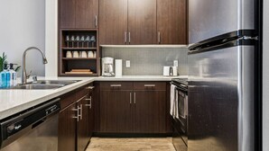 Eine moderne Küche mit dunklen Holzausführungen, Edelstahlgeräten, einem Geschirrspüler und einer Kaffeemaschine.