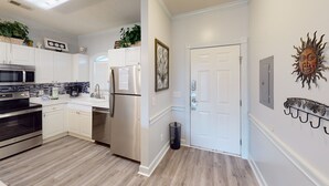 Une cuisine moderne avec des meubles blancs, des appareils en acier inoxydable et un plancher en bois.