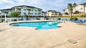 Une piscine avec des chaises longues et une clôture blanche.