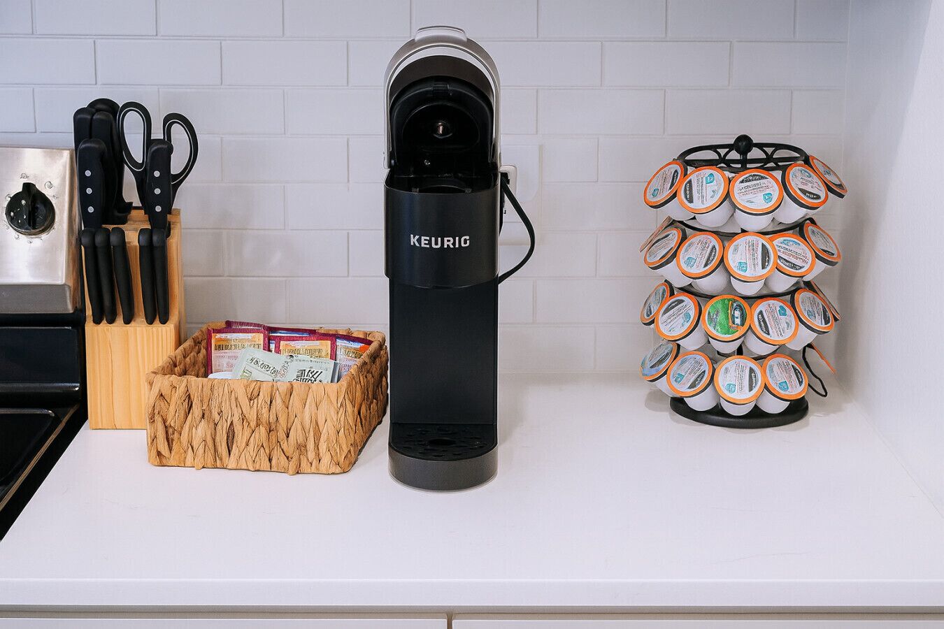 A kitchen with a coffee maker, a knife block, and a basket of coffee pods.