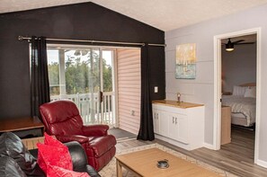 A cozy room with a red leather chair, a small wooden table, and a kitchenette. - Waterway Village 18G (Myrtle Beach)