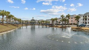 A water feature with a gazebo, surrounded by palm trees and a row of buildings. - Waterway Village 18G (Myrtle Beach)