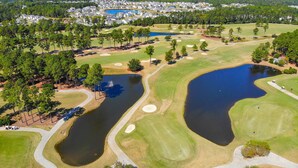 Luftaufnahme eines Golfplatzes mit mehreren Teichen, umgeben von Wohngebieten und dichten Wäldern.