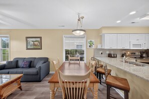 A modern kitchen with white cabinets, a granite countertop, and stainless steel appliances. - River Oaks 5C (Myrtle Beach)