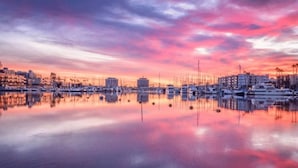 A marina with boats and buildings reflecting on calm water during sunset. - Cozy Marina Hideaway Gym, Pool & Spa Central (Marina del Rey)