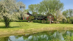 A red building with a lawn and a pond. - Old Orchard House (Brandon)