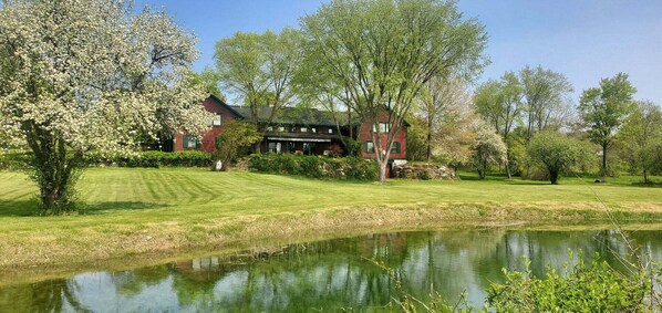 A red building with a lawn and a pond. - Old Orchard House (Brandon)