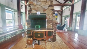 A rustic kitchen with a stone wall, wooden beams, and a green pot on the stove. - Old Orchard House (Brandon)