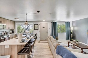 A modern kitchen with a central island, dining area, and a living space with a sofa and a TV. - Comfortable 2BR Apt Near Capitol Hill & SLC (Salt Lake City)