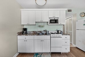 A compact kitchen with white cabinets, a microwave, a stove, and a refrigerator. - Myrtle Beach Resort B 435 (Myrtle Beach)