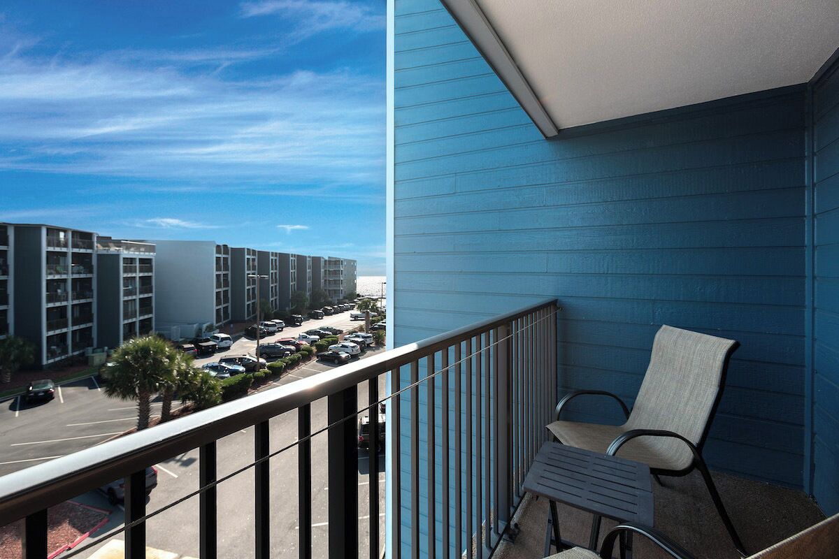A balcony with a view of a parking lot and buildings.