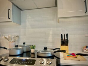 A kitchen with a stove, pots, a plant, and a knife block. - Modern&cozy, Washer/dryer, Pool,gym,workerfriendly (Sherman)
