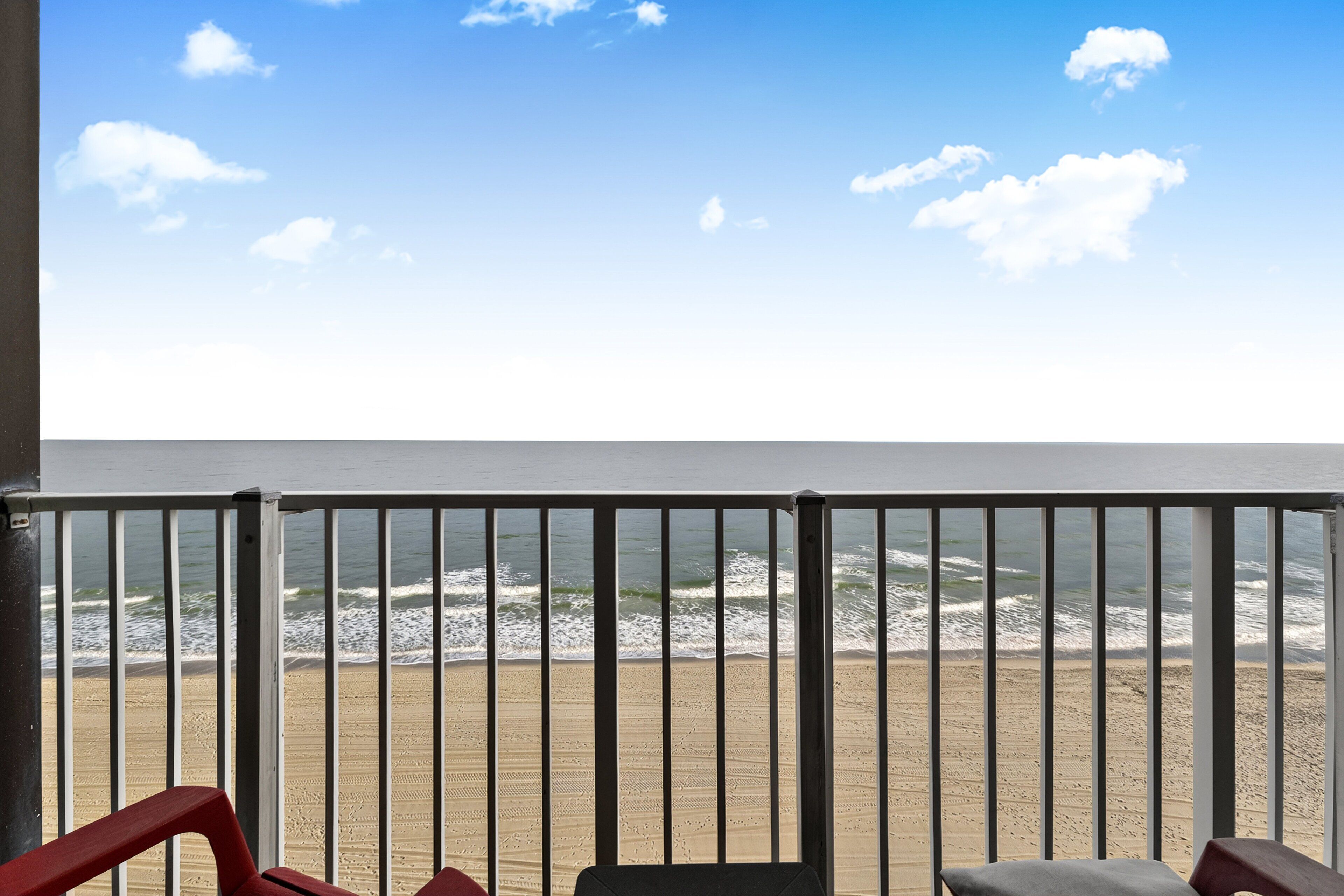 A balcony with a view of the beach and ocean.