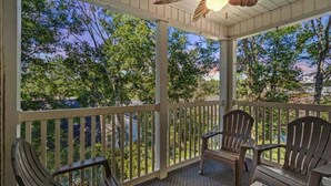 A covered porch with wooden chairs and a ceiling fan. - Maison Place I (Myrtle Beach)