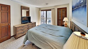 A hotel room with a bed, dresser, television, lamp, and a painting on the wall. - Shipwatch Pointe I F217 (Myrtle Beach)