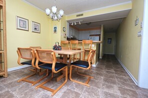 Ein Essbereich mit einem runden Tisch, sechs Stühlen, einer Kronleuchter und einer Küche im Hintergrund.