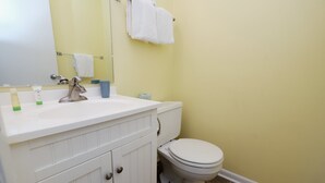 Et badeværelse med et hvidt håndvask, spejl og toilet.