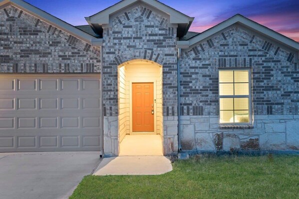 Une maison à deux étages avec une façade en pierre, un garage et une porte d’entrée.