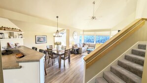 Eine geräumige Küche mit Essbereich, ein Wohnzimmer mit Sofa und Couchtisch sowie eine Treppe, die in eine weitere Ebene führt.