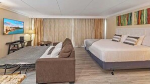 A hotel room with a bed, a sofa, a desk, and a TV. - Marbella Lane - Ocean Marina View Ilikai Hotel (Honolulu)
