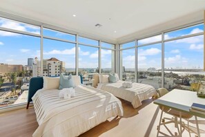 A hotel room with two beds, a desk, and large windows offering a city view. - Marbella Lane - Grand 2BR w Beach & Ocean Views (Long Beach)