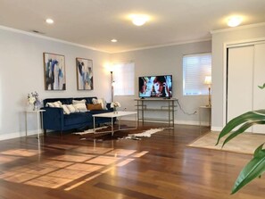 A living room with a blue sofa, a coffee table, a TV, and a plant.