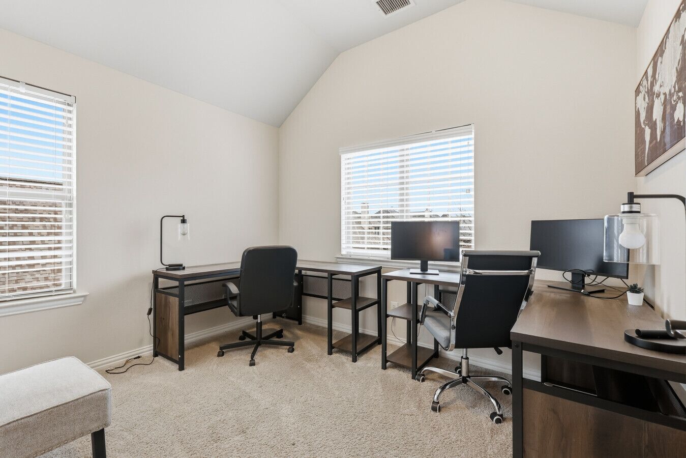 A modern office space with two desks, two chairs, and two monitors.