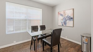 A conference room with a glass table, four chairs, a painting on the wall, and a trash can. - Luxe 3B 5B Cozy, Spacious Home, 5-star Stay in Frisco (Frisco)